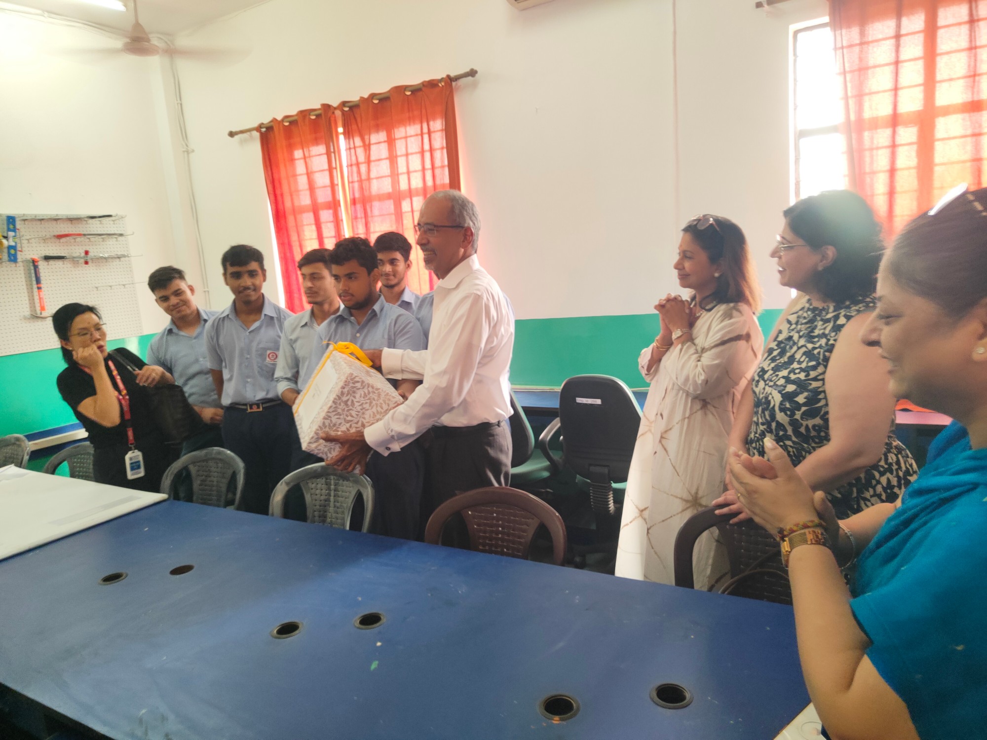 An ICRA volunteer presenting a gift to students at a skilling centre